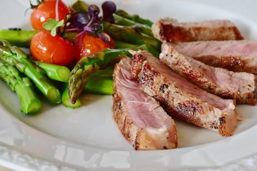 Close-up of grilled steak slices with asparagus and cherry tomatoes, perfect for a healthy meal.