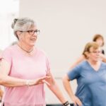 Senior women participating in a lively and joyful group exercise session indoors.
