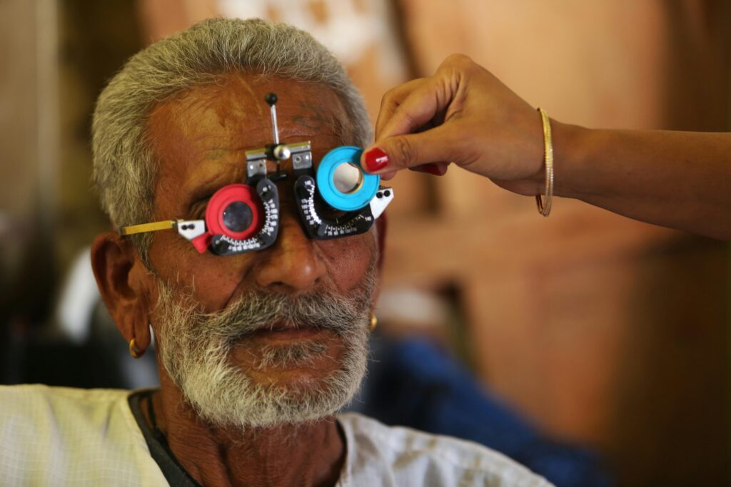 Senior man having vision test with trial lens set during eye exam.