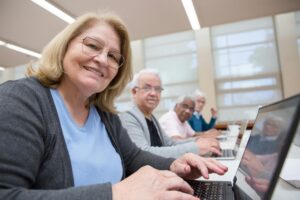 Group of senior adults using laptops for a digital learning session in a modern indoor setting.