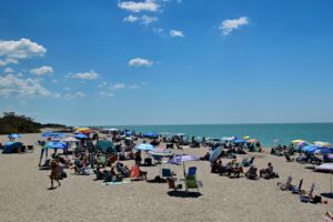 Crowded beach with colorful umbrellas in Venice, Florida.
