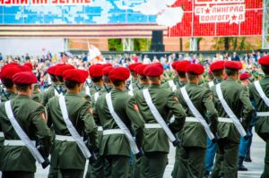 Back view of soldiers in green military uniforms and red berets during a parade.