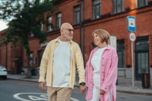 Elderly couple walking outside, holding hands with joyful expressions. Perfect for lifestyle themes.