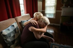 An emotional and supportive embrace between a couple on a sofa, showcasing affection and togetherness in a cozy home setting.