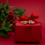 Gold rings elegantly placed on a red Christmas gift box with festive decoration.