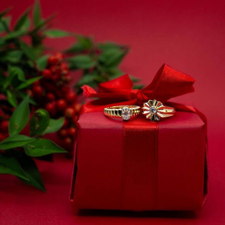 Gold rings elegantly placed on a red Christmas gift box with festive decoration.