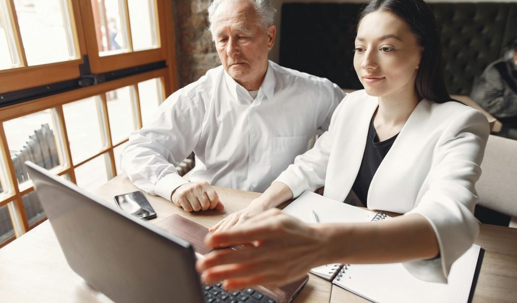 Adult professionals sharing ideas and collaborating on a project using a laptop in an indoor setting.