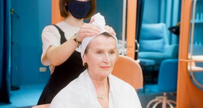 A senior woman is pampered with a hair treatment in a salon, highlighting the professional care provided.