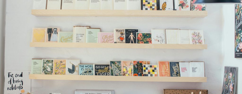 Interior of modern light shop with wooden shelves with various books and stationery composed with creative decorative elements