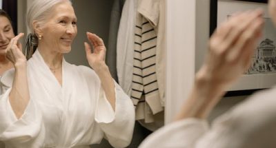 Senior woman in bathrobe smiling at her reflection in the bathroom mirror