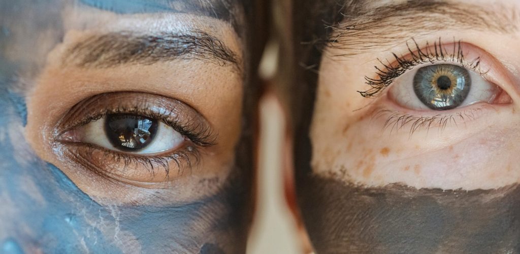 Closeup portrait of two women with facial masks, highlighting diversity and skincare routines.